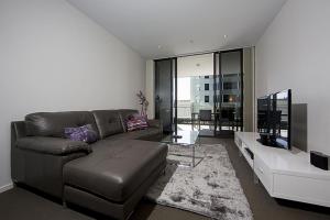 a living room with a leather couch and a television at Manhattan 303 Canberra City ACT in Canberra