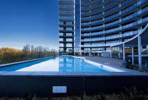 an empty swimming pool in front of a tall building at Manhattan 303 Canberra City ACT in Canberra