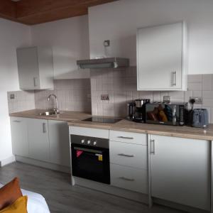 una cocina con armarios blancos y horno negro en Eighty Four, en Birmingham