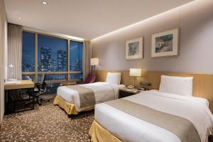 a hotel room with two beds and a desk and a window at Holiday Inn Incheon Songdo by IHG in Incheon +72 photos