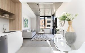 a kitchen and living room with white furniture and a vase with flowers at Azure 30 in Kingston 