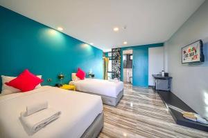 um quarto com 2 camas e uma parede azul em Nam Naka Boutique Hotel - SHA Plus em Phuket