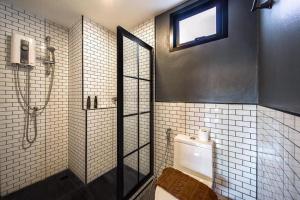 a bathroom with a shower and a toilet and a window at Nam Naka Boutique Hotel - SHA Plus in Phuket Town