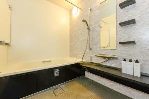 ein Badezimmer mit einem Waschbecken und einer Badewanne in der Unterkunft Hostel Sapporo Hachijo Bettei in Okadamachō