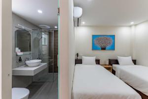 two beds in a hotel room with a bathroom at Edoya hotel Dong Khoi in Ho Chi Minh City
