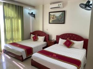 um quarto de hotel com duas camas e uma janela em Tom's Family Hotel em Ha Long