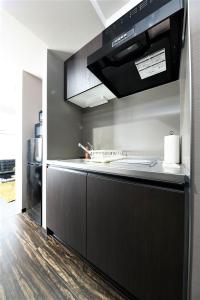 a kitchen with a black counter and a refrigerator at MJステイズ in Kita-rokujō