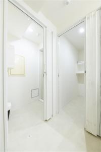 a white hallway with a mirror and a closet at MJステイズ in Kita-rokujō