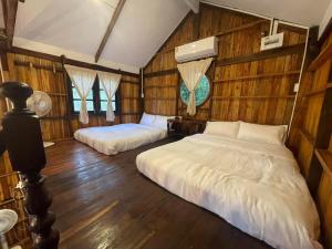 Ban Don KlangにあるBaanraipoonwana Baanboonmakのベッド2台 木製の壁の部屋