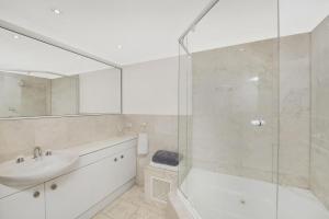 uma casa de banho branca com um lavatório e um chuveiro em The Summit E2 Kingston ACT em Kingston 
