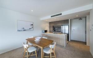 a kitchen and dining room with a wooden table and chairs at Lakefront Apartments Kingston ACT in Kingston 