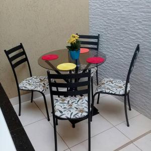 特林達德的住宿－Casa com 2 quartos e banheira de Hidromassagem，一张桌子、四把椅子和一张桌子,上面有鲜花