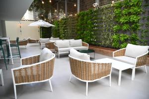 a patio with wicker chairs and tables and a wall at The Muse Boutique Hotel Tel Aviv in Tel Aviv