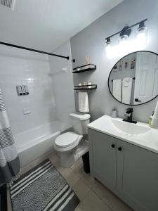 ein Badezimmer mit einem Waschbecken, einem WC und einem Spiegel in der Unterkunft Bohemian 1 Bedroom- Minutes from Busch Gardens in Tampa
