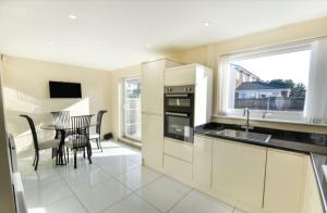 a kitchen with a sink and a table with chairs at 3 bed House Lovely & Modern in Whitefield