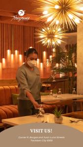 Eine Frau steht in einem Restaurant und trägt eine Maske. in der Unterkunft Ironwood Hotel in Tacloban