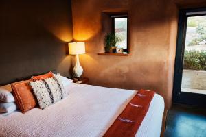 a bedroom with a bed with pillows and a lamp at Sacred Sands in Joshua Tree