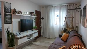 a living room with a couch and a tv at Casa Duplex Praia do Peró - Cinema em Casa in Cabo Frio