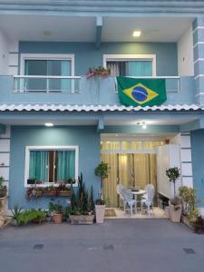 una casa azul con una bandera en el balcón en Casa Duplex Condomínio Ipanema no Peró en Cabo Frío