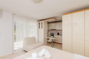 um quarto branco com uma cama branca e uma cadeira em CACTUS - Blooming Garden Apartments em Kalamata