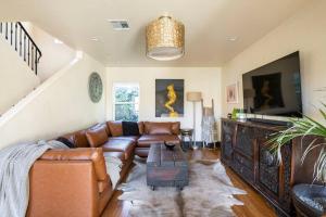 a living room with a leather couch and a flat screen tv at Spanish Gem Summer Stay, Filming Events Day Use in Los Angeles