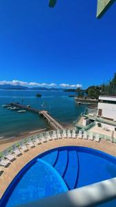 - une vue sur une plage avec des chaises et une piscine dans l'établissement angra dos reis, condomínio angra inn, à Angra dos Reis