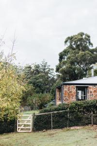 una casa de ladrillo con una puerta y una valla en Naivasha Cottage, en Deloraine