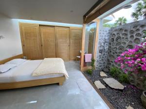 Un dormitorio con una cama y algunas flores púrpuras en Villa Cantik Sambirenteng en Gretek
