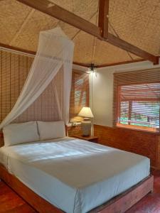 1 dormitorio con 1 cama con mosquitera en Mookies Bungalows, en Ko Mook