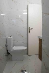 a white bathroom with a toilet and a door at Volos City Center 1 in Volos