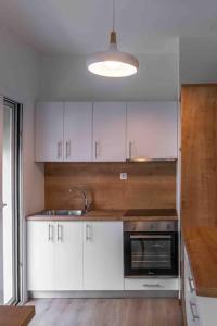 a kitchen with white cabinets and a sink and a stove at Volos City Center 1 in Volos