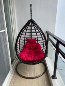 墾丁星院旅宿 في كنتيج: كرسي أرجوحة مع وسادة حمراء في الغرفة
