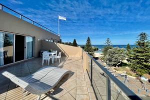 uma varanda com uma mesa e cadeiras e o oceano em Coogee Sands Hotel & Apartments em Sydney