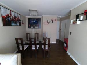 uma sala de jantar com uma mesa e cadeiras e uma televisão em Casa con estacionamiento en sector residencial em Puerto Montt