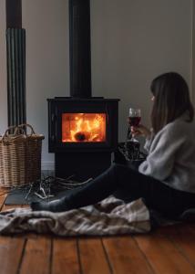 a woman holding a glass of wine in front of a fireplace at Naivasha Cottage in Deloraine