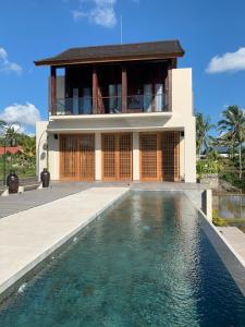 a villa with a swimming pool in front of a house at Umah Tirta Estate in Ubud