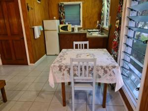 uma cozinha com uma mesa, 2 cadeiras e um frigorífico em Sunny Beach Bungalows - Aitutaki em Amuri