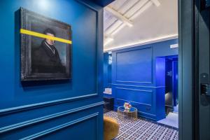 un couloir bleu avec une peinture d'un homme dans l'établissement Palazzetto Trevi, à Rome