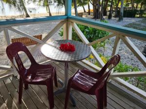 uma mesa e duas cadeiras num alpendre em Sunny Beach Bungalows - Aitutaki em Amuri