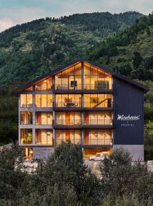a large glass building with a mountain in the background at Warehouse X Poshtel in Manāli
