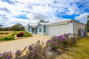 una casa con un garage bianco e fiori viola di Luxury home on a 100 acre block a Preston Beach