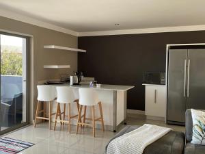 a kitchen with a counter and stools in a room at Treklaer Lodge in Hartenbos +13 photos