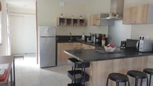 a kitchen with a counter with stools and a refrigerator at Gite des Cépages in Voiteur