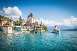 a large boat in the water next to a castle at -The Urbanist- Lakeview Free Parking 2BD Fast WiFi in Oberhofen am Thunersee