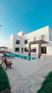 een groot wit gebouw met een zwembad ervoor bij Lammah chalet in Muscat