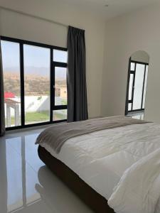 a bedroom with a bed and a large window at Lammah chalet in Muscat