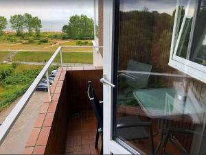 a balcony with a table and chairs and a window at Appartement Strandnest Meerblick strandnah by Unsere Urlaubszeit in Grömitz