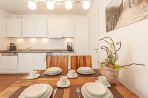 a kitchen with white cabinets and a table with white dishes at Appartement Strandläufer mit Südbalkon by Unsere Urlaubszeit in Binz