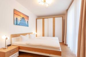 a bedroom with a white bed and a large window at Appartement Strandläufer mit Südbalkon by Unsere Urlaubszeit in Binz