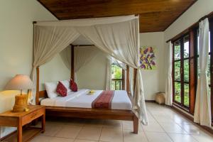 - une chambre avec un lit à baldaquin dans l'établissement Sarin Ubud Suites by Pramana Villas, à Ubud